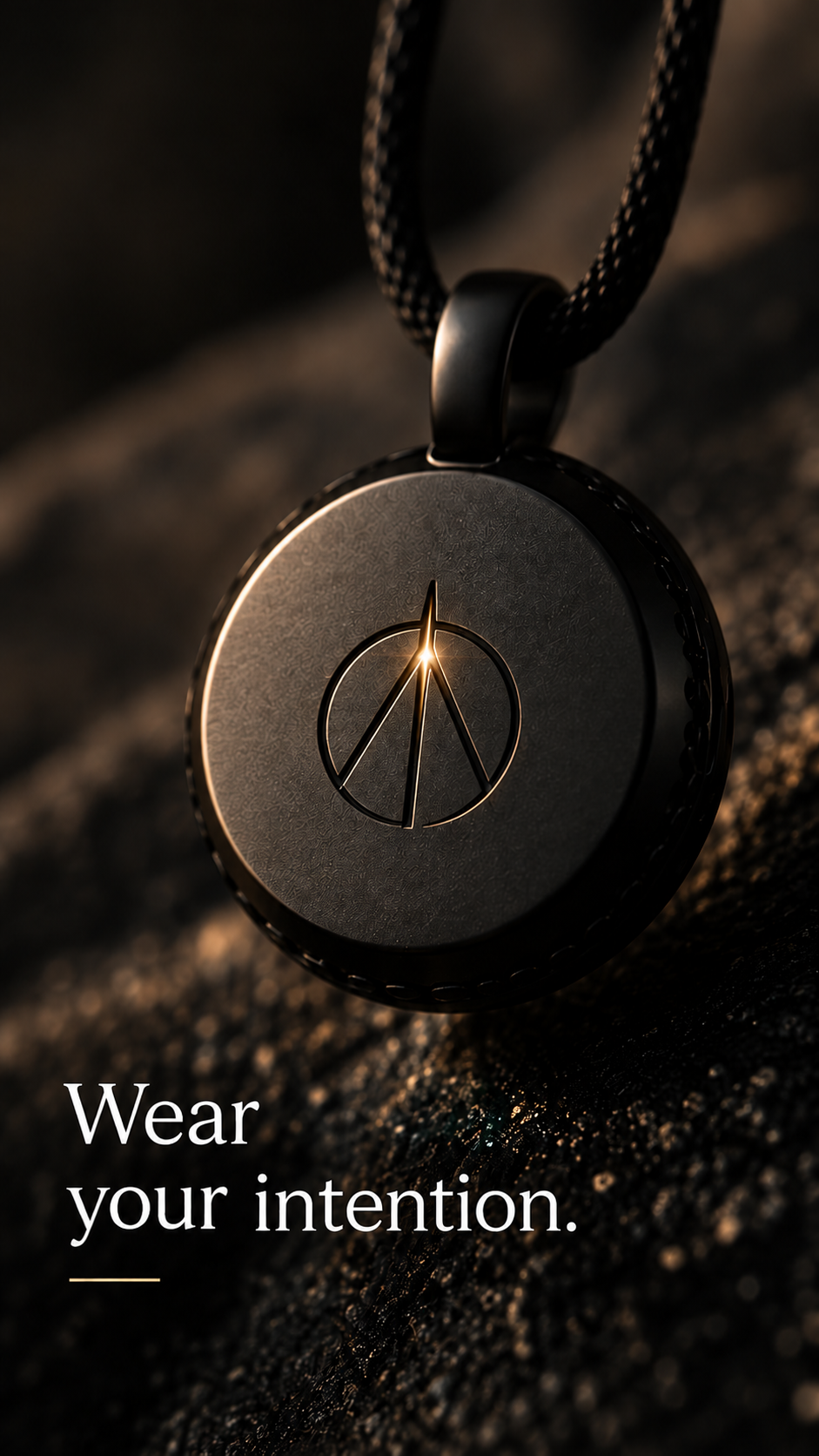 Dark-metal ATRACTA pendant with the new engraved symbol illuminated in gold, on a black cord. Wear your intention.